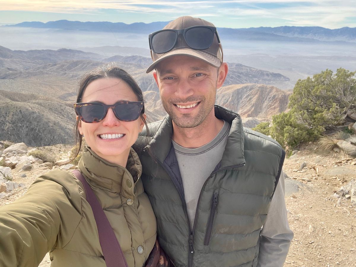 The husband-and-wife owners of Emanti Property Maintenance, smiling together at a mountain overlook.