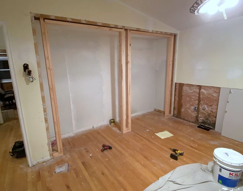 A bedroom with two closet openings framed in bare lumber.