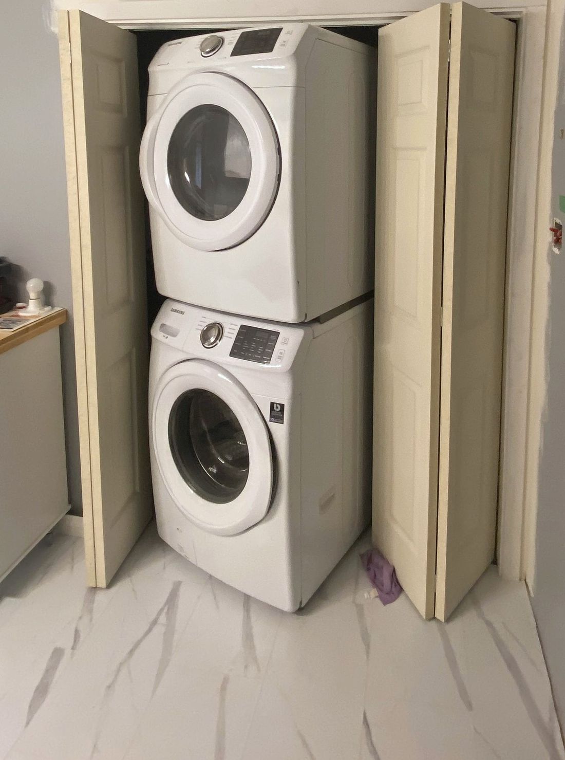 The same closet with folding doors hung and a stacked washer and dryer inside.