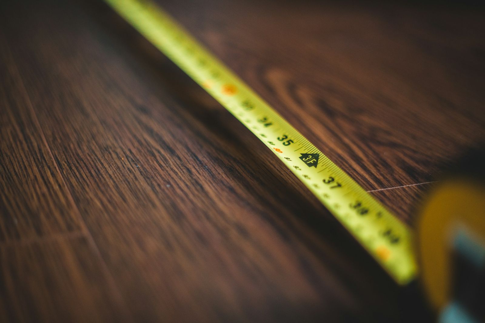 A yellow tape measure laid across dark wood.